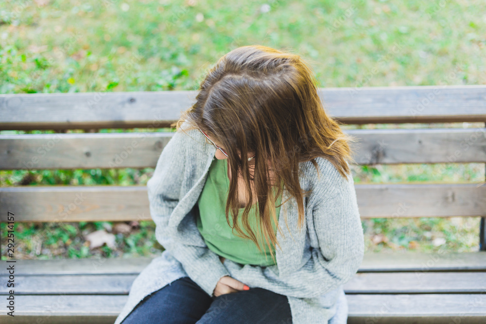Woman suffering from menstrual pain while holding her belly outdoors