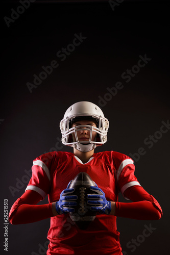 Photo of American woman football player in helmet with rugby ball in her hands on blank black background