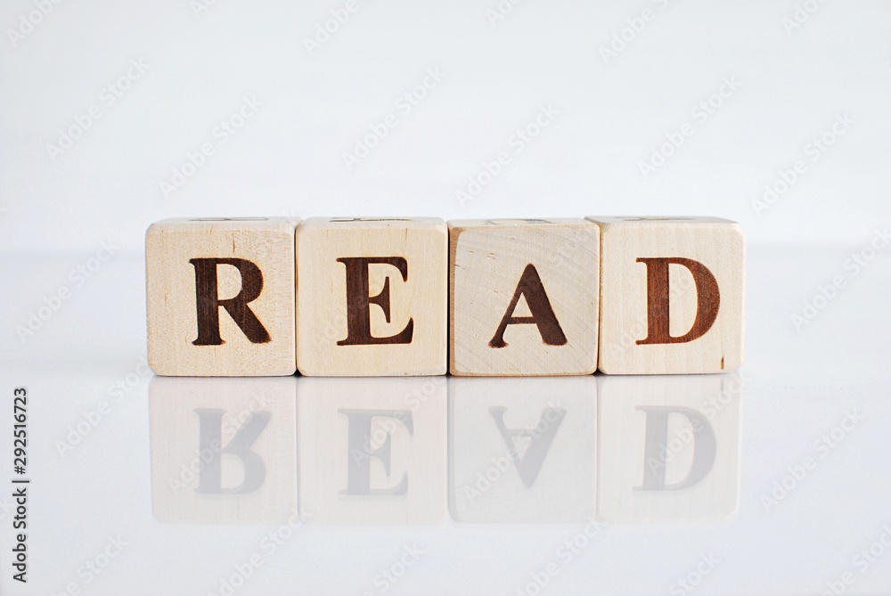 Wooden cubes word READ on white background with reflection.