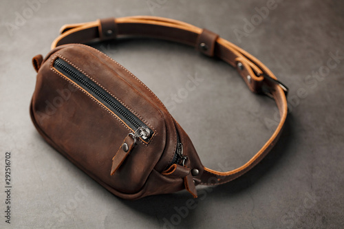 Handmade genuine brown leather on a dark background Brown belt bag. Elegant brown bag with a zipper