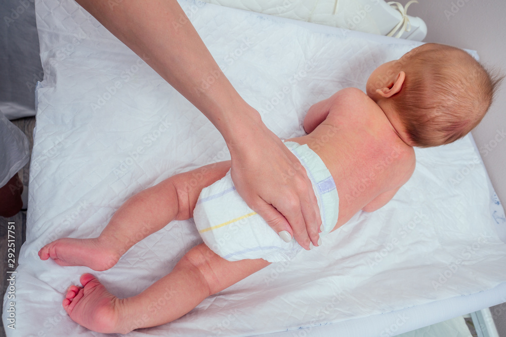 caucasian mother applying baby powder before putting diapers on her