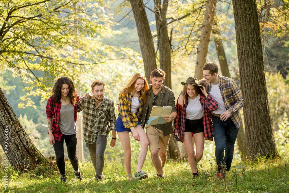 Obraz premium positive young tourists walking with a map in the forest, full length photo. travel, adventure, people