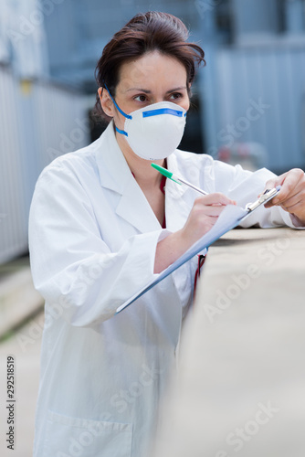 woman with a mask checking clipboard