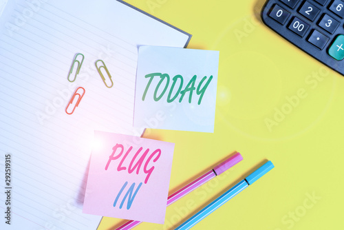 Text sign showing Plug In. Business photo showcasing putting device into electricity to turn it on Power it Connecting Empty blue paper with copy space paper clips and pencils on the yellow table