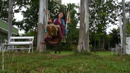 Thai woman sit relax and playing on wooden bench swings toy in garden of resort at riverside Mae Khlong or Meklong river in Ban Pong at Ratchaburi Province, Thailand photo