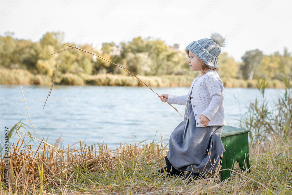 Cute little girl playing by the water on beautiful autumn day. Autumn activities for children. Cute little girl playing by the water on beautiful autumn day. Autumn activities for children.