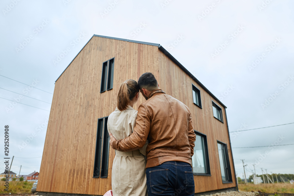 Couple stand and look at big new house