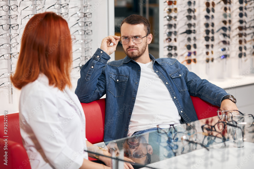 Obraz premium serious man wearing glasses looking at the oculist expressing negative feeling and emotion, close up photo