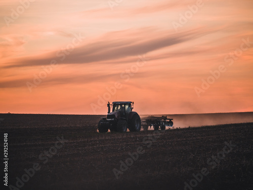 Tractor on filed by sunset.