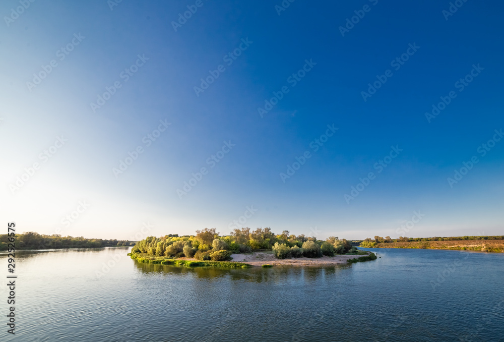 Island on the river against the blue sky at sunset.