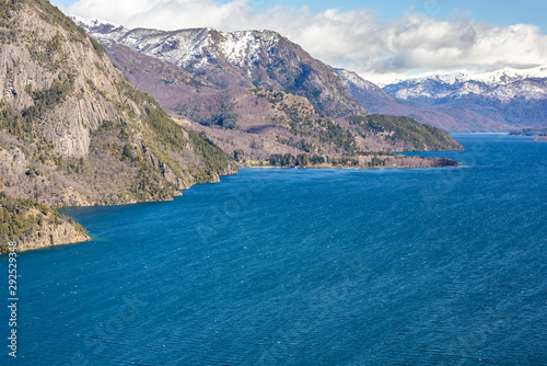 An amazing view of Lacar Lake coast with a bare tree and the Patagonia landscape in the Seven Lakes Route at Argentina. An amazing and inspirational road trip with awesome mountains with huge lakes 