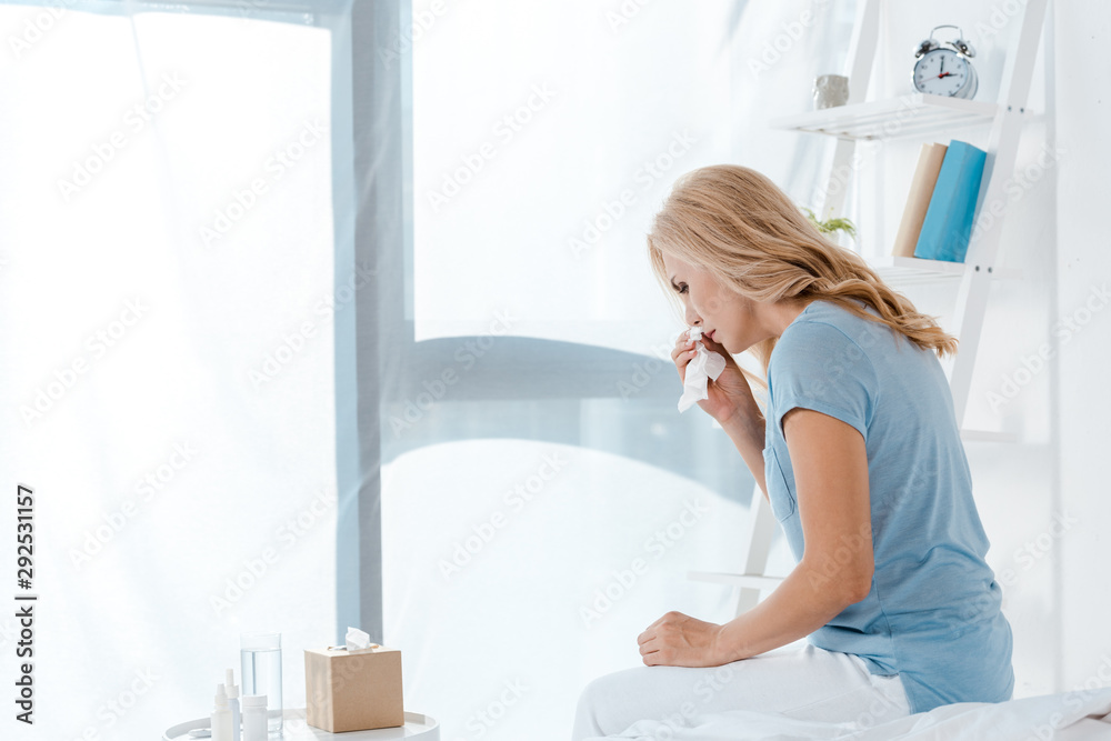 sick woman sitting on bed and holding napkin sick woman sitting on bed and holding napkin