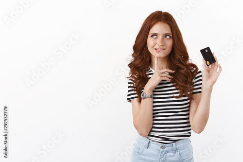 Hmm girl think how waste money boyfriends bank account. Cute thoughtful redhead female student got salary, hold credit card, biting lip curious and thoughtful, look sideways, ponder choices
