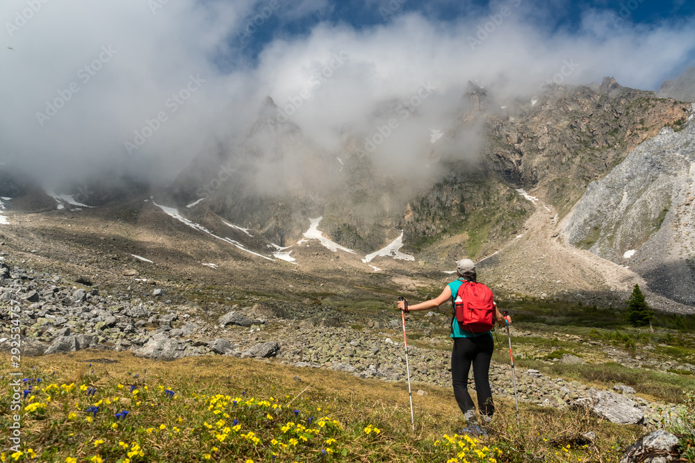 Tourist girl stands under the top of a mountain