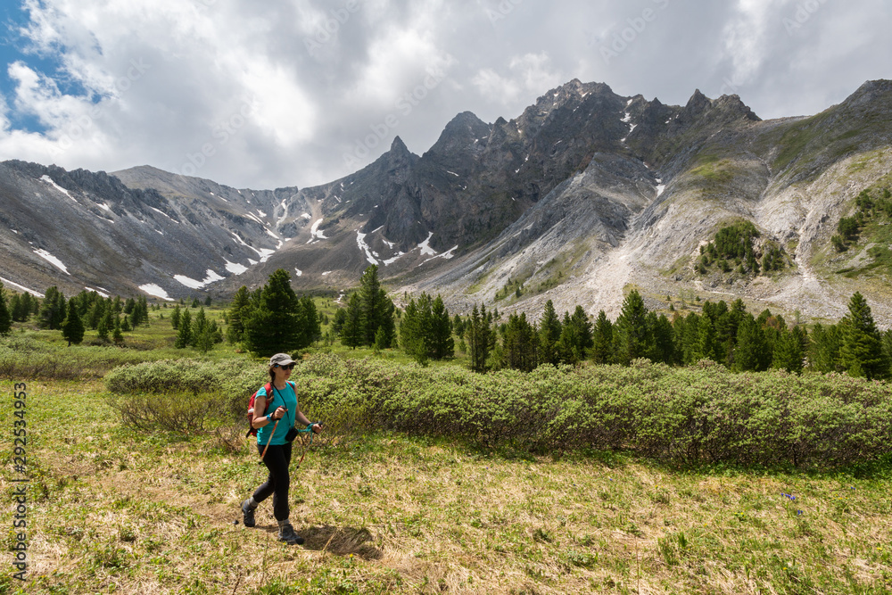 Tourist girl goes hiking in Eastern Sayan Mountains
