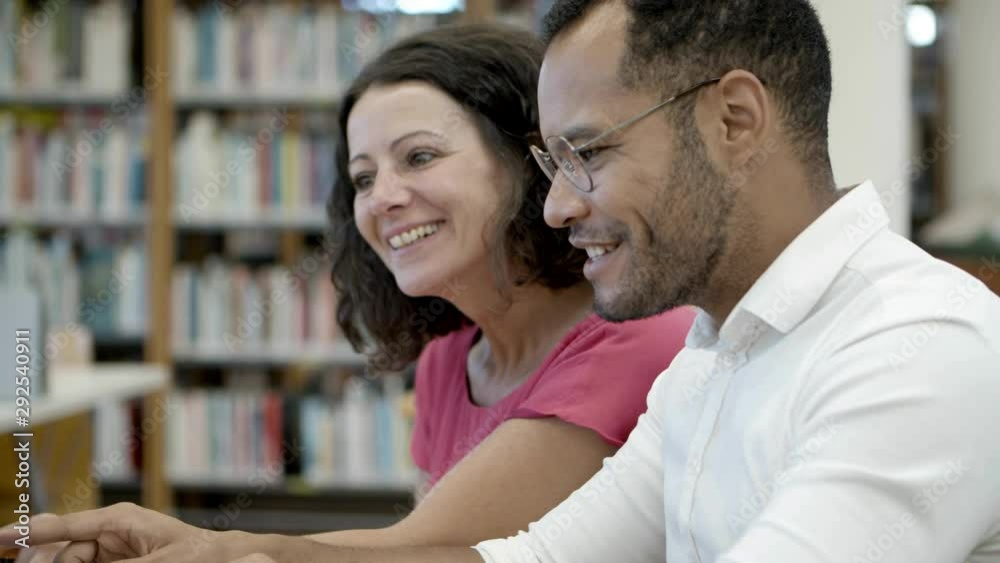 Smiling people communicating at library. Side view of cheerful students studying at library. Education concept Smiling people communicating at library. Side view of cheerful students studying at library. Education concept