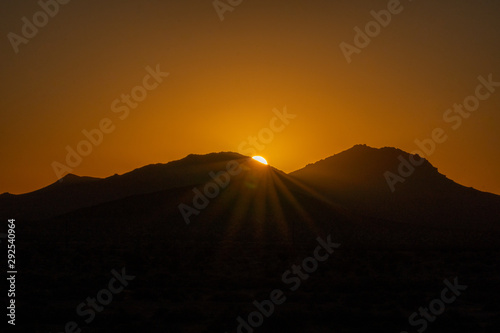 Sun peaking over mountains at sunrise in the mojave desert © FroZone