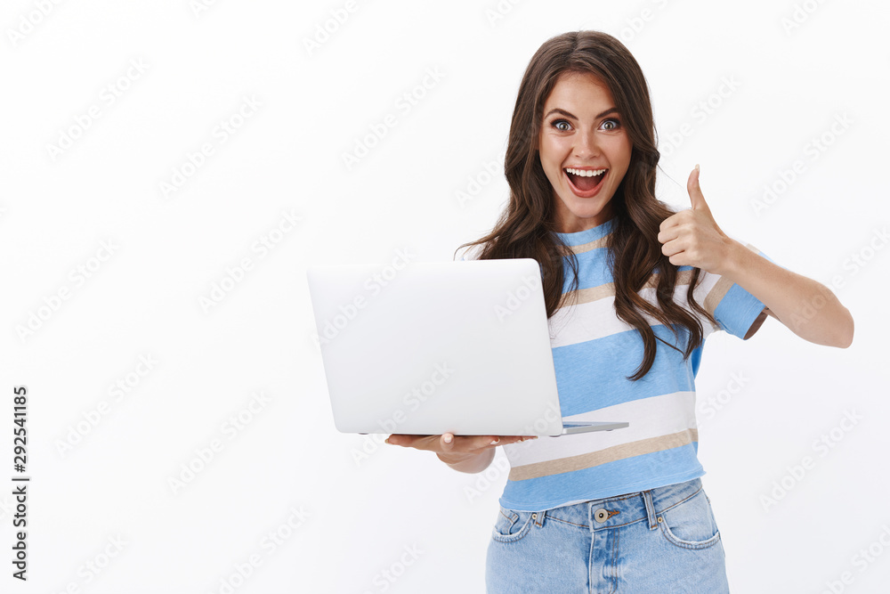 Lively satisfied modern gorgeous woman picked cool computer, smiling broadly hold laptop, show thumb up in approval, accept gesture, like cool friend project music-video, leave positive comment Lively satisfied modern gorgeous woman picked cool computer, smiling broadly hold laptop, show thumb up in approval, accept gesture, like cool friend project music-video, leave positive comment
