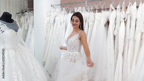 Young beautiful woman in a wedding dress is spinning in a wedding salon.