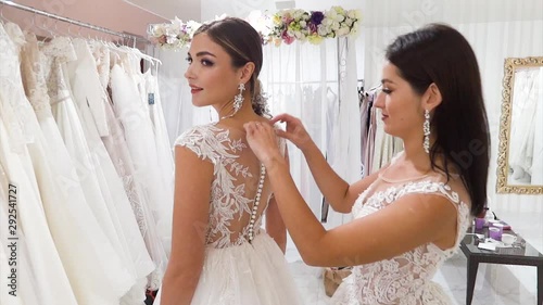 Two young women in wedding dresses posing in a bridal salon.