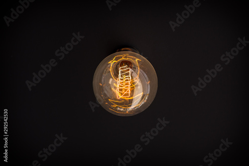 Old-fashioned light bulb turned on. On the dark surface, the concept of creativity photo