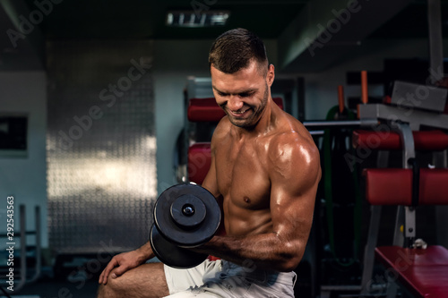 muscular bodybuilder doing exercise on bars in the gym. a handsome, sporty, sexy guy with a abs training in the gym. fitness, bodybuilding, nutrition, healthy lifestyle