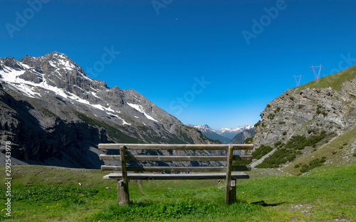 Relaxing panoramic view over the italian alps, with a bench in front of the mountains