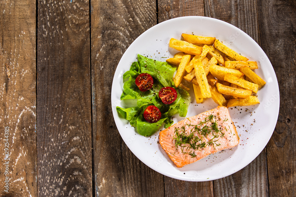 Fried salmon with french fries on wooden table
