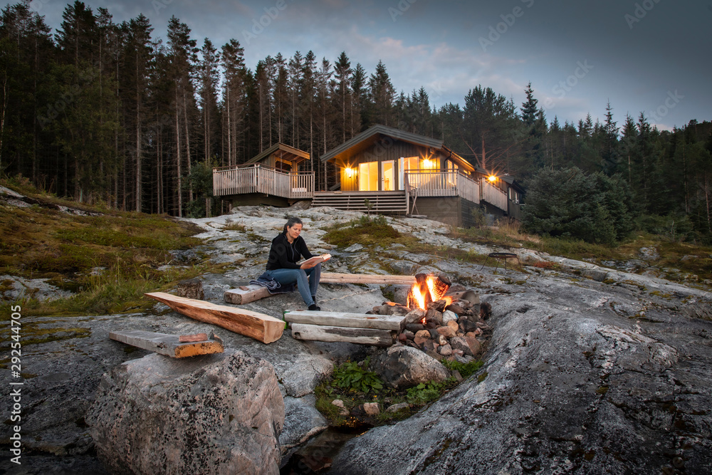 woman reading beside campfire in norway