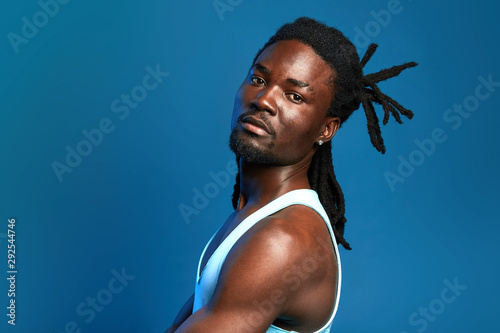Valokuva handsome strong man in white top, vest having a break after workout, close up portrait, isolated blue background, studio shot