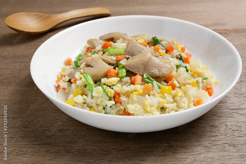 close up of fried rice with chicken and vegetables in a ceramic plate on wooden table. homemade style food concept. close up of fried rice with chicken and vegetables in a ceramic plate on wooden table. homemade style food concept.