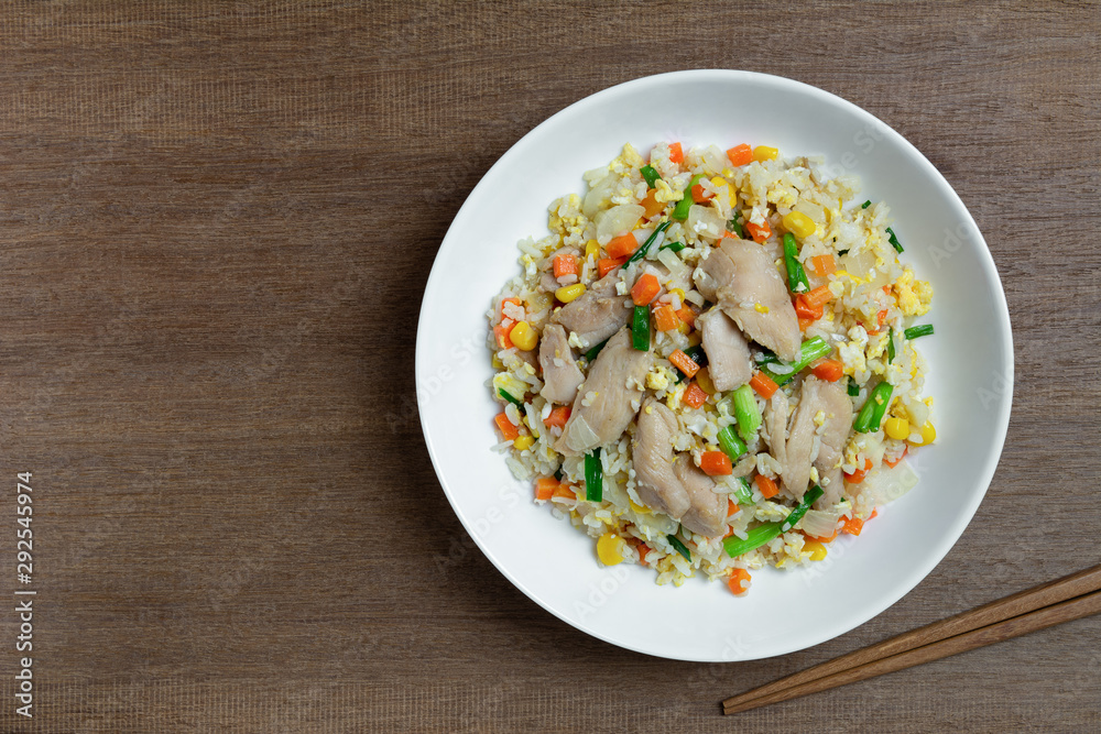 top view of fried rice with chicken and vegetables in a ceramic plate on wooden table. homemade style food concept. top view of fried rice with chicken and vegetables in a ceramic plate on wooden table. homemade style food concept.