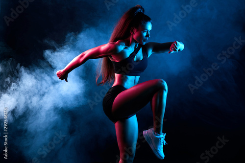 motivated ambitious woman running in the black studio. health and body crea, wellness, hobby, interest. close up side view photo