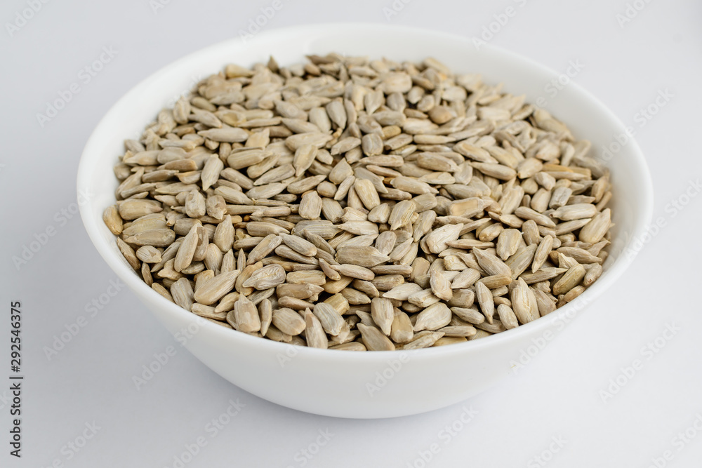 Freeh raw organic sunflower seeds in a white round bowl on a table in soft focus, isolated on white, top view Freeh raw organic sunflower seeds in a white round bowl on a table in soft focus, isolated on white, top view