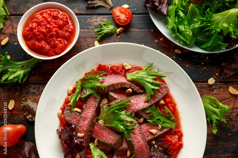 Beef Steak with Romesco sauce, nuts and vegetables on white plate Beef Steak with Romesco sauce, nuts and vegetables on white plate