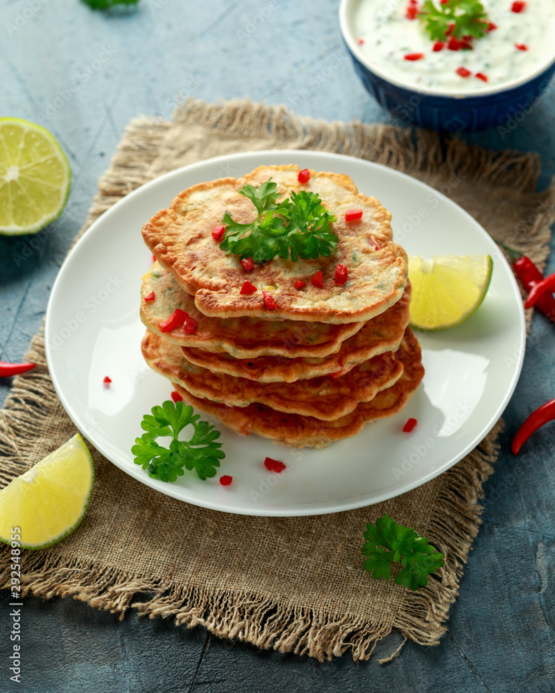 Corn fritters, pancake with dip white sauce, lime and chilli on white plate