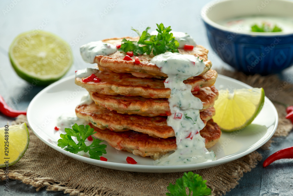 Corn fritters, pancake with dip white sauce, lime and chilli on white plate Corn fritters, pancake with dip white sauce, lime and chilli on white plate