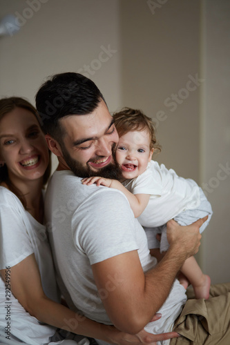 cheerful daddy and mommy hugging their kid, they adore her. warm feeling and emotion, happiness