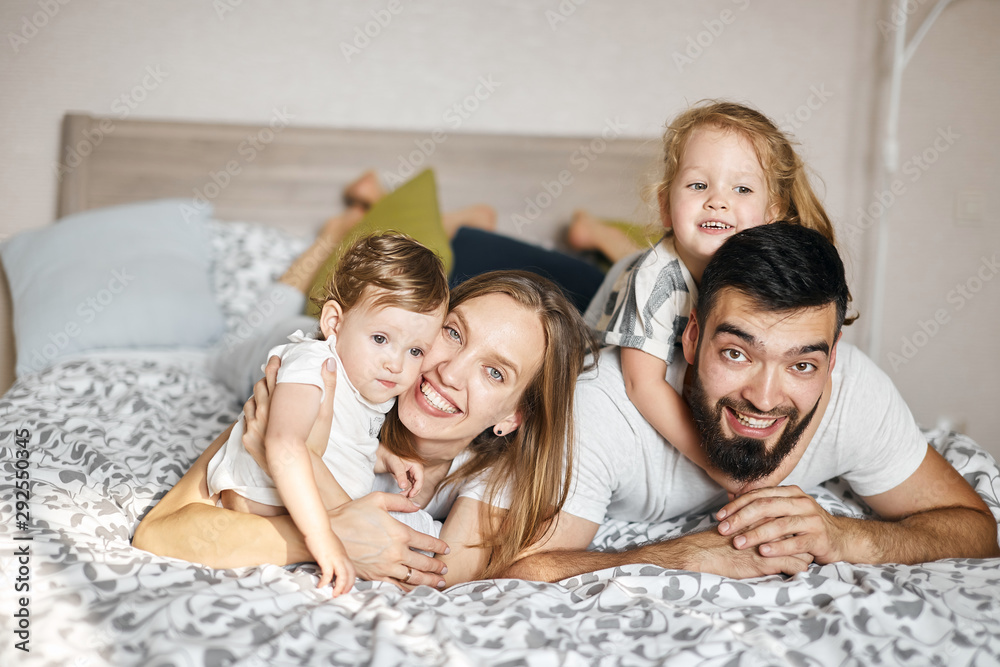 Happy cheerful friendly family lying on the bed, looking at the camera. relationship. close up photo. love, positive emotion and feeling