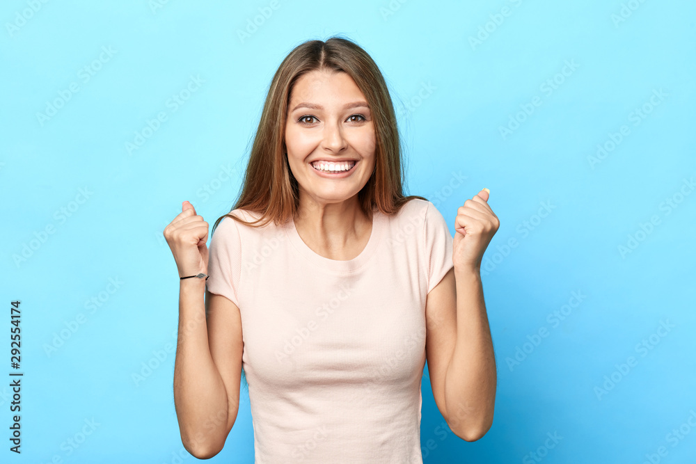 Happy smiling woman rejoicing at her winning, holiday, birthday. close up portrait, happiness, reaction, facial expression, body language. isolated blue background, studio shot