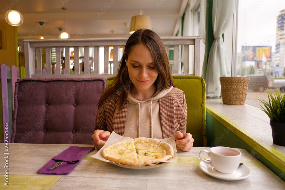 Young Woman eating pizza in the cafe. Delicious pizza with Round Pear Slices, Roquefort Blue Cheese served at Italian Restaurant with Plate. 