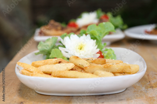 French fries decorted with vegetable and flower on white plate. photo