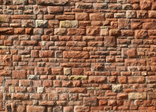 large red old sandstone wall with rough textured surface