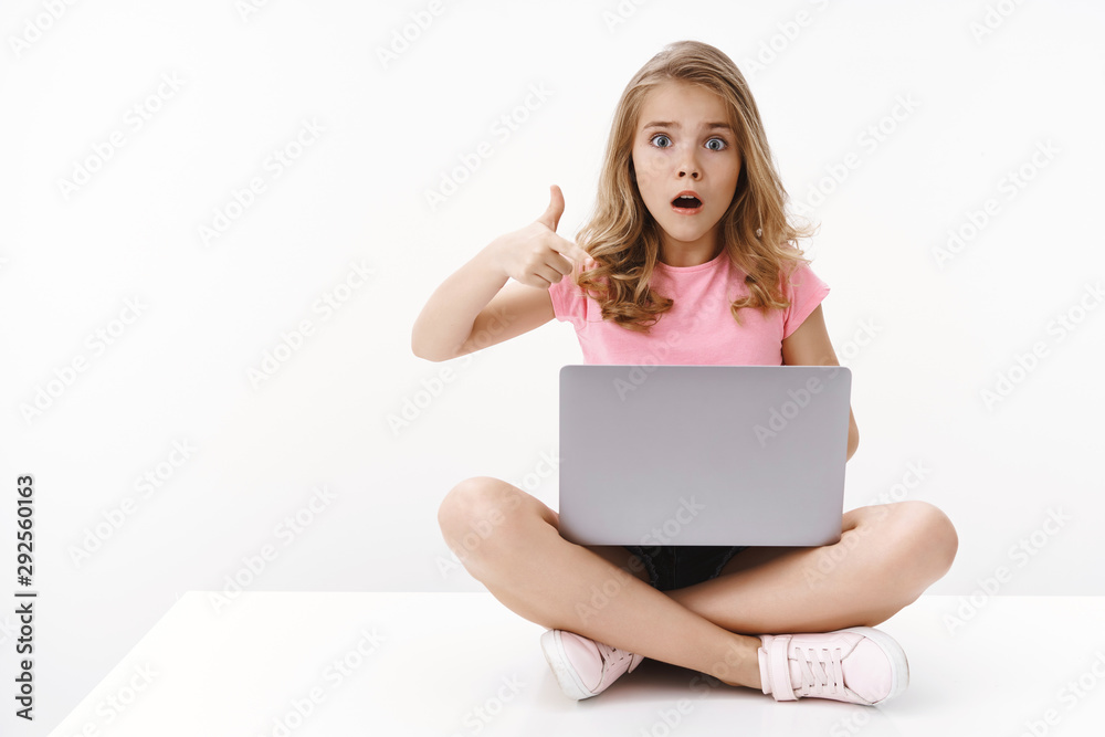 Shocked worried cute blond girl little daughter show mom scary video computer, sit crossed legs, hold laptop, pointing gadget screen, gasping scared and nervous, stare camera upset, white background Shocked worried cute blond girl little daughter show mom scary video computer, sit crossed legs, hold laptop, pointing gadget screen, gasping scared and nervous, stare camera upset, white background