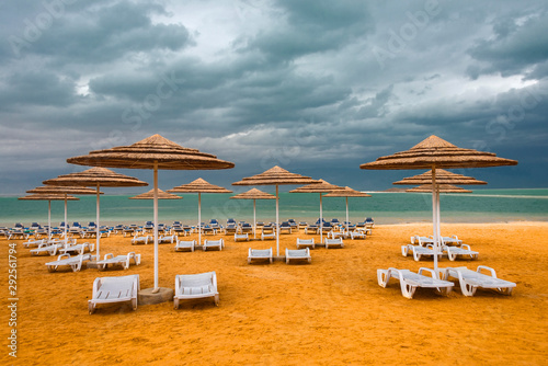 Sunshade and chaise lounges against the yellow sand on the empty seashore