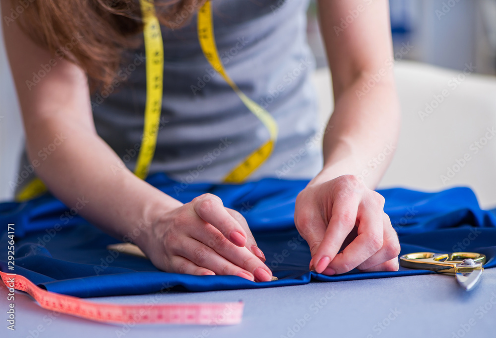 Woman tailor working on a clothing sewing stitching measuring fa