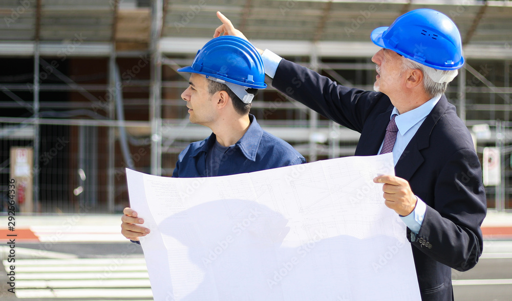 Two architect developers reviewing building plans at construction site
