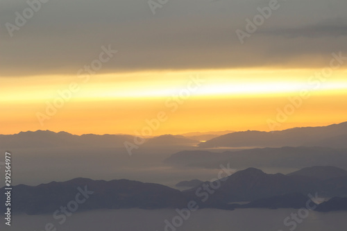 Mediterranean landscape. Sunset on the sea with flowing bright colored rays of the sun through the clouds. Silhouettes of mountains. Background, blur.
