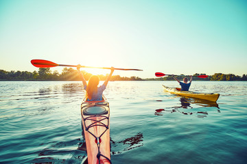 People kayak during sunset in the background. Have fun in your free time.