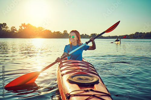 Canvas Print People kayak during sunset in the background